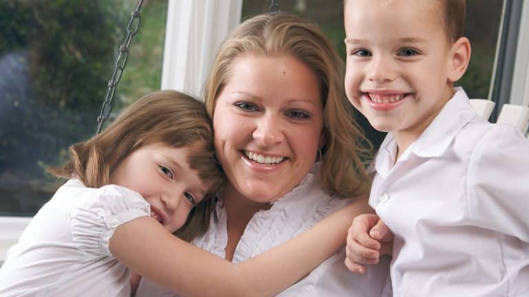 A mother holding her two young children, a son and daughter