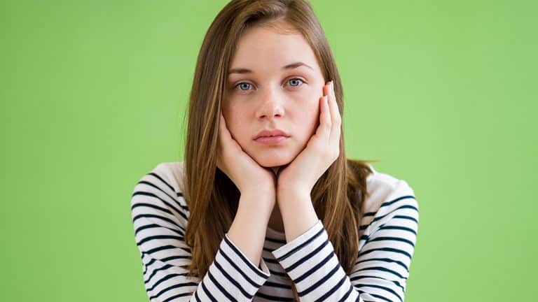 Sad student sitting in classroom with her head in hands.