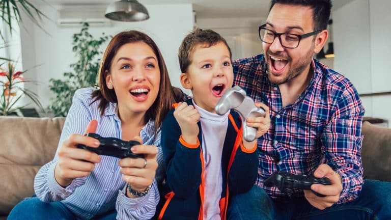 Happy family sitting on a sofa and playing video games.