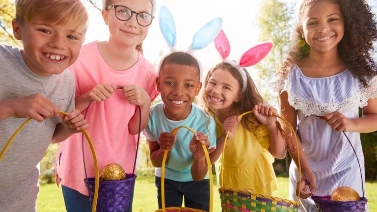 Portrait Of Five Children Wearing Bunny Ears On Easter Egg Hunt In Garden making Easter fun for Kids.