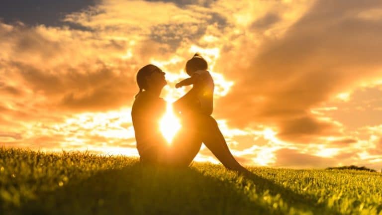 An image of a mother and her young child set against a backdrop of sunrise in early morning.