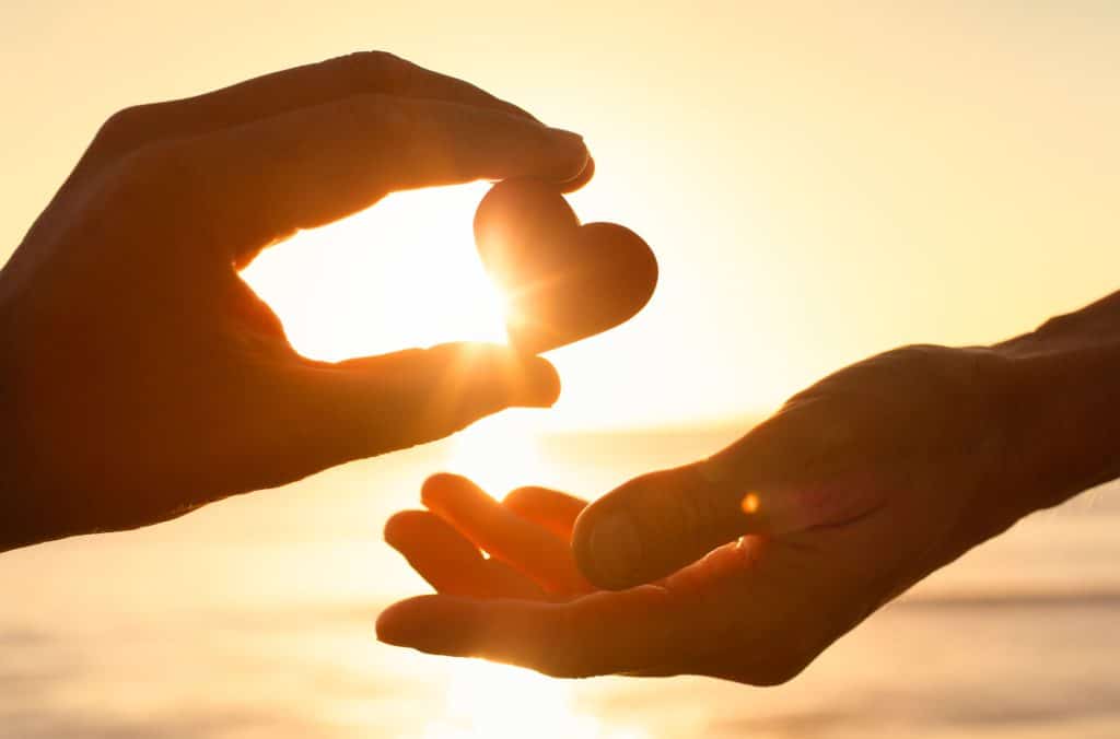 A photo of a hand passing heart to another.