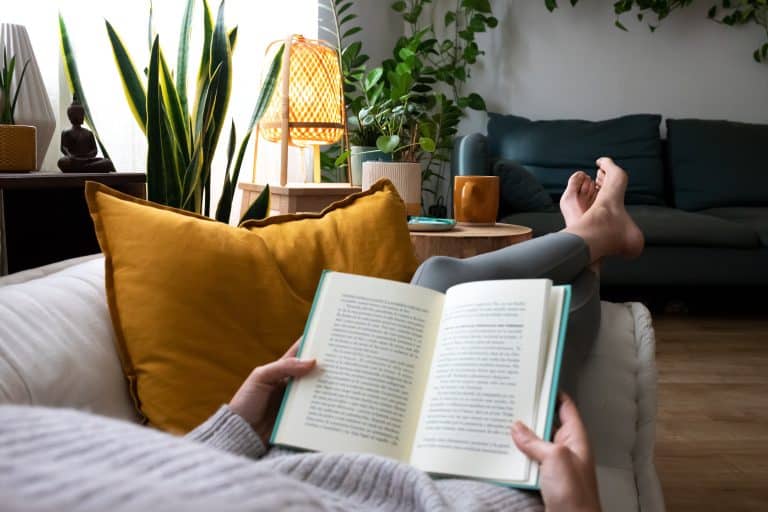 photo of a woman reading a book on her couch
