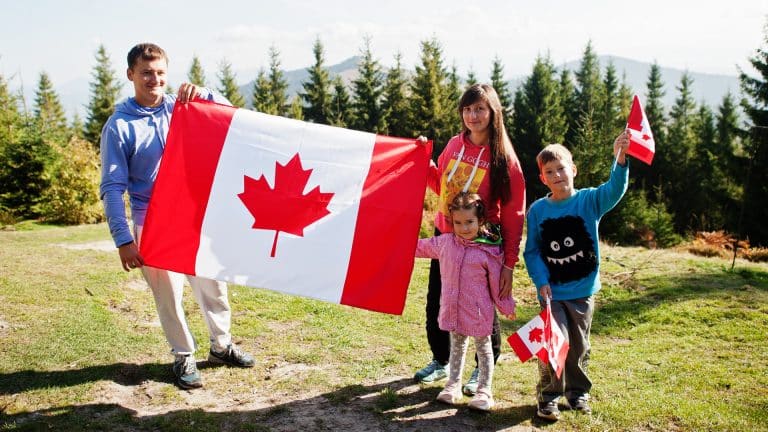 Happy Canadian Family holding a Canadian Flag on Victoria Day Long Weekend